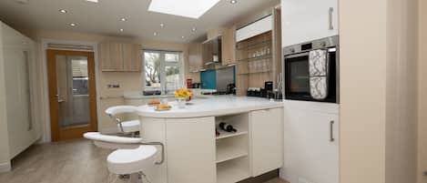 A modern kitchen with a central island, built-in appliances, and a large window.