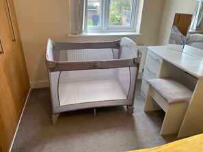 A room with a crib, a desk, and a window. - Modern 4-Bed House | Windsor | Driveway + Garden (Windsor)
