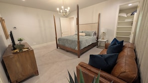 Quarto com cama de dossel, mesa de cabeceira de madeira, sofá de couro e armário embutido.