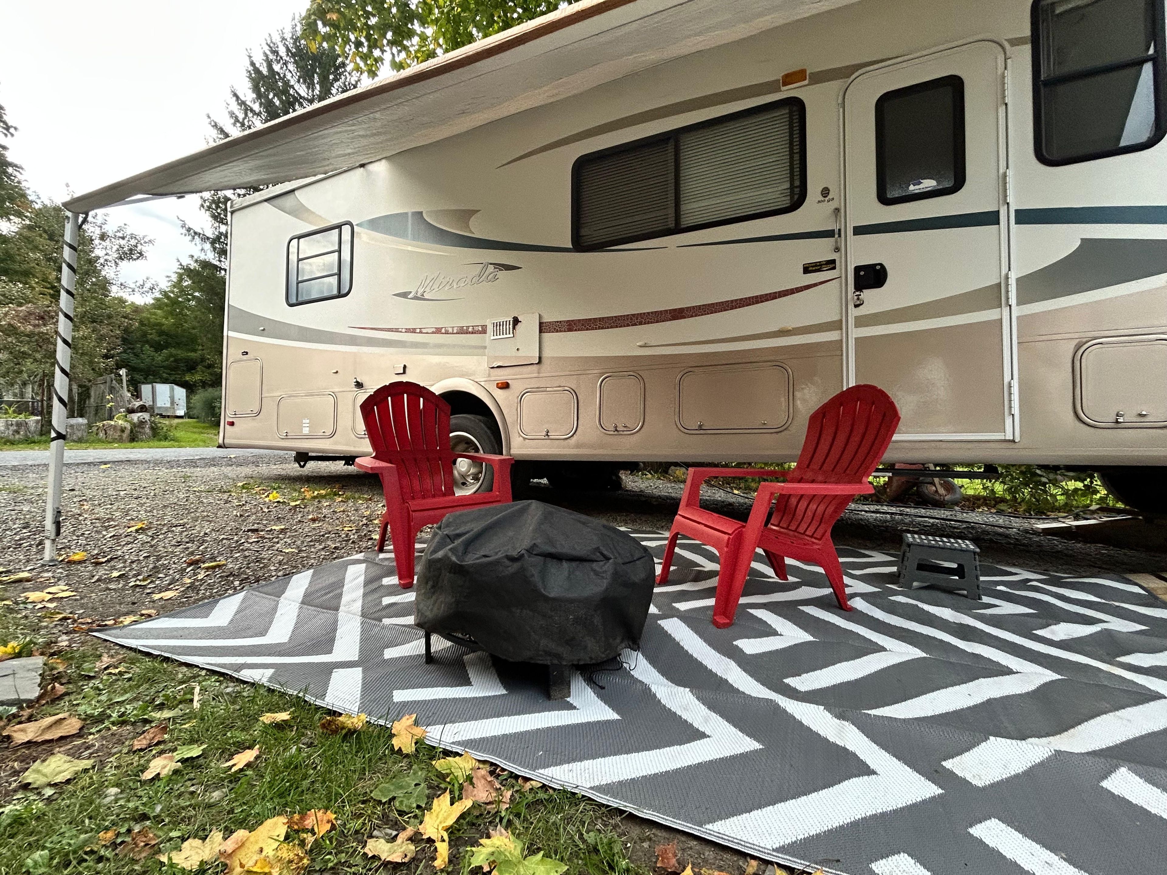 Een recreatievoertuig met twee rode stoelen en een zwart object op een patroonmat.