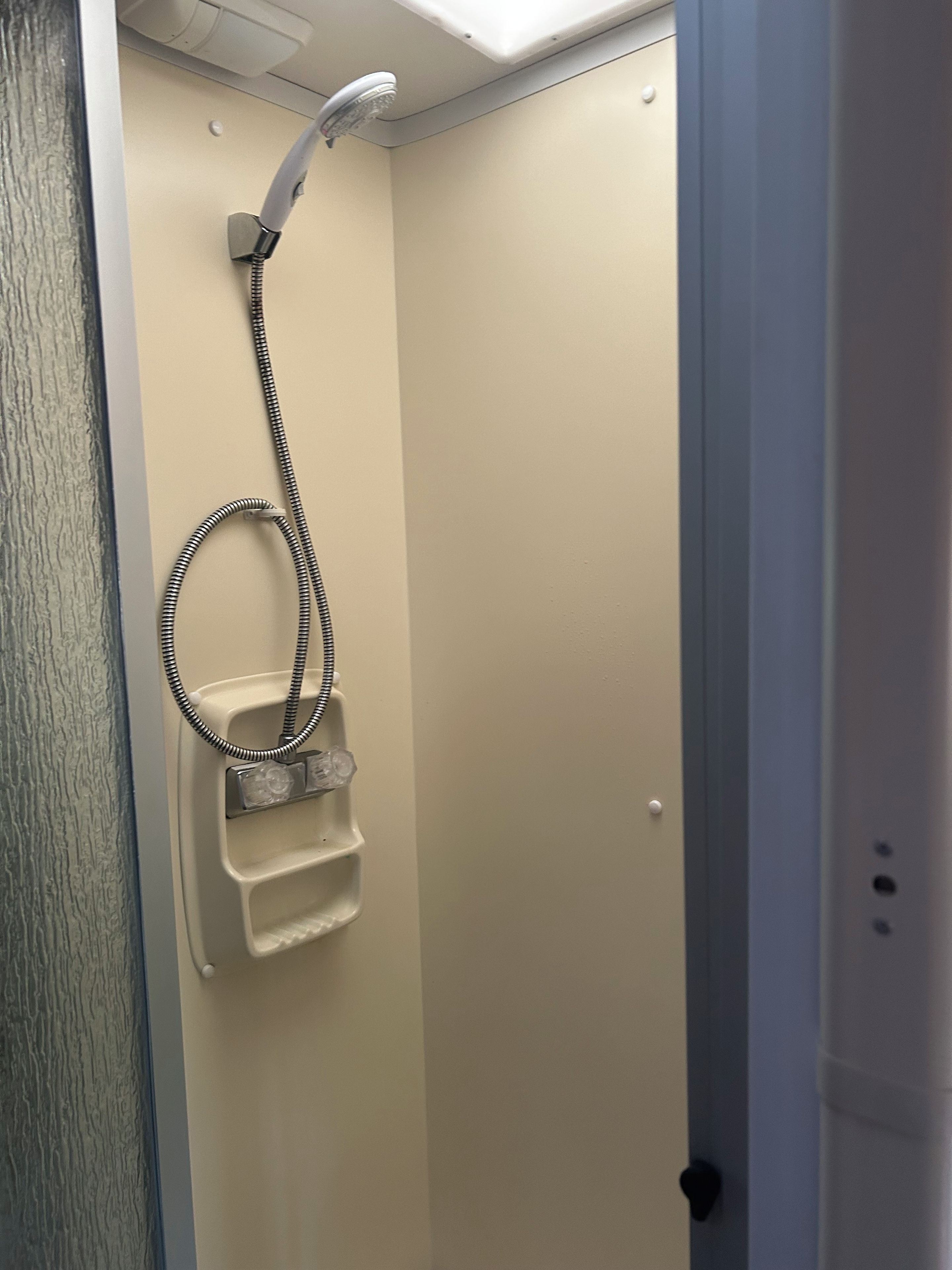 A shower with a handheld showerhead and a handheld basin.