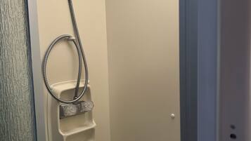 A shower with a handheld showerhead and a handheld basin.