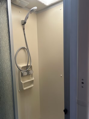 A shower with a handheld showerhead and a handheld basin.