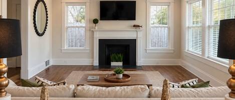 A living room with a fireplace, a television mounted above it, and a sofa with decorative vases.