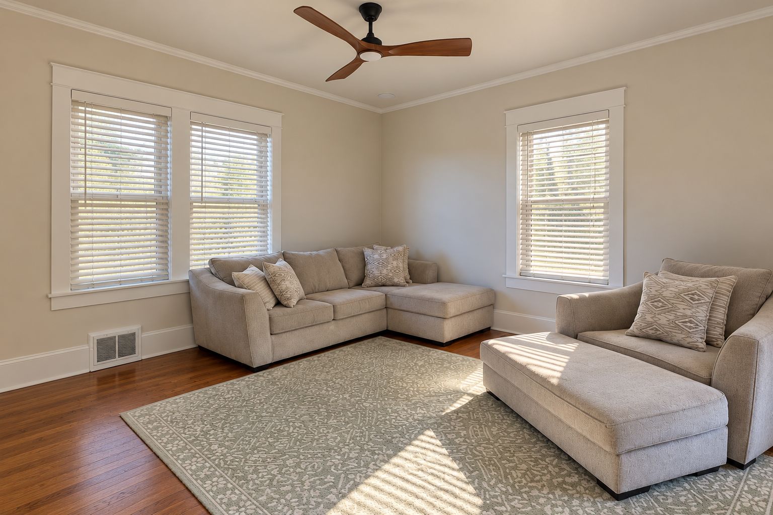 Un salon avec un canapé d’angle, un ventilateur de plafond et un tapis à motifs.