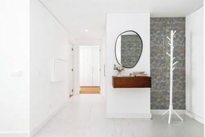 Ein moderner Flur mit einer weißen Tür, einem Holzschrank mit Spiegel und einer strukturierten Wand.