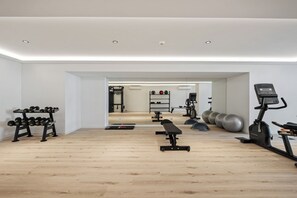 Ein modernes Fitnessstudio mit Holzboden, Trainingsgeräten und einer Bank.