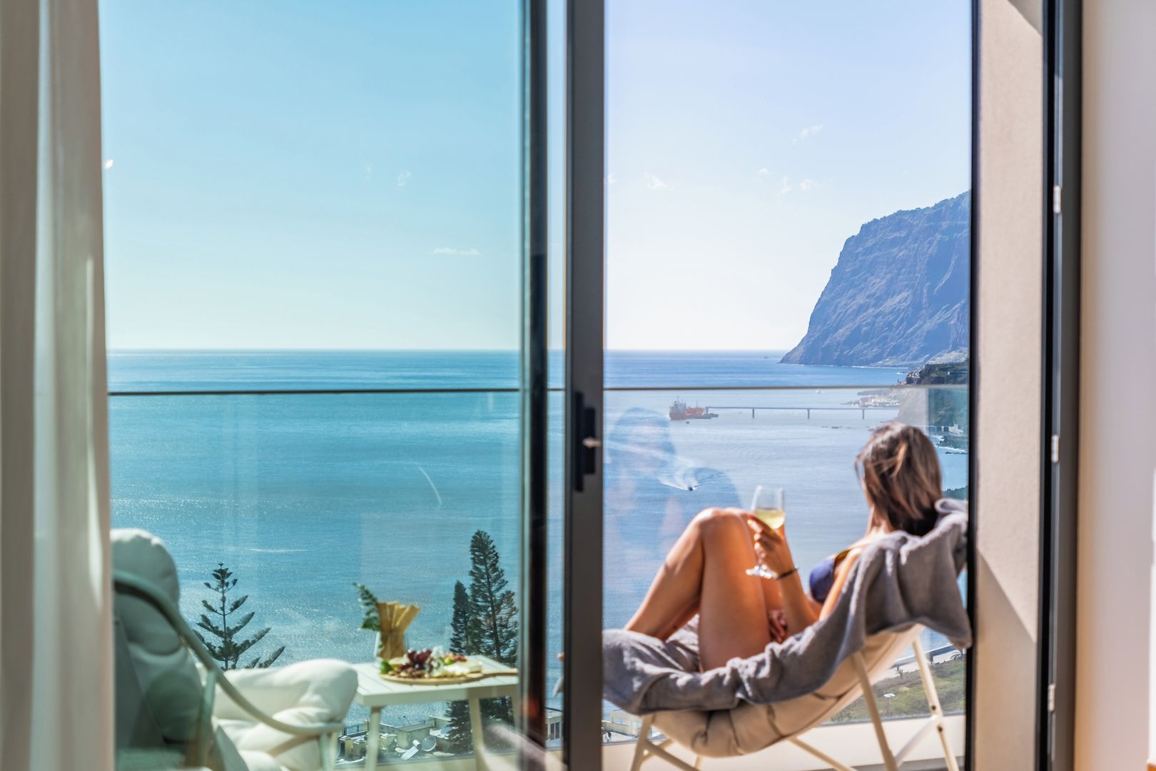 A balcony with a clear view of the sea and a mountain.