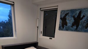 A modern bedroom with a bed, a window, and a painting on the wall. - A little retreat in Seattle perfect for your next getaway (Seattle)