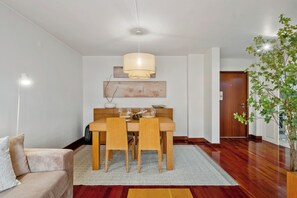 Ein Essbereich mit Holztisch und Stühlen, einer Pendelleuchte und einem Blumentopf.