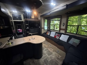 Uma cozinha compacta com ilha central, forno embutido e área de refeições com banco e almofadas.