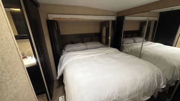 A hotel room with two beds, a mirror, a wardrobe, and a bathroom.