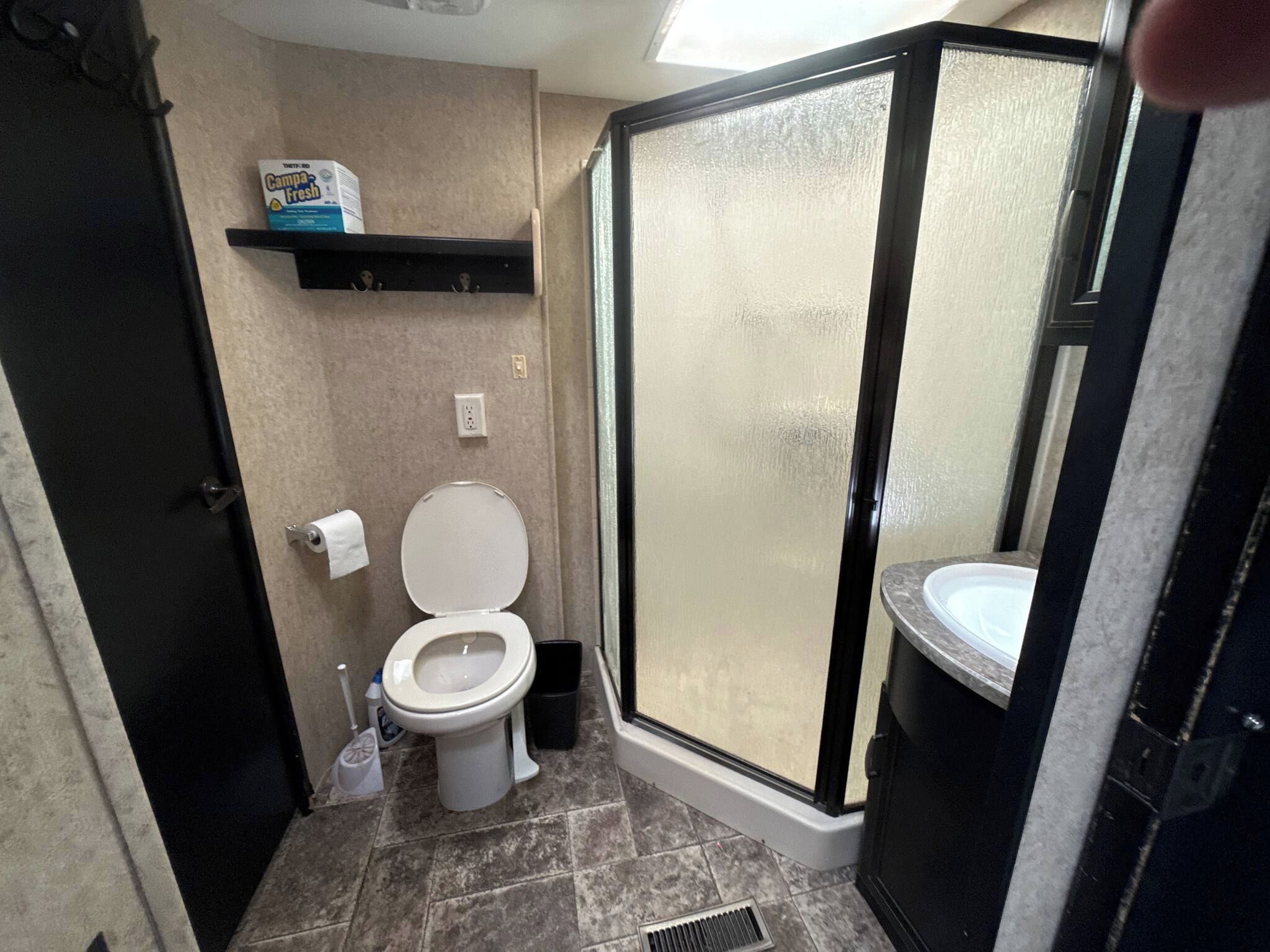 A bathroom with a toilet, a shower enclosure, and a sink.