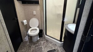 Et badeværelse med toilet, bruseniche og håndvask.