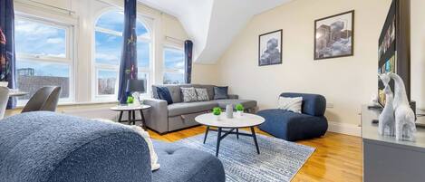 Una sala de estar moderna con un sofá, dos sillones, una mesa de centro y un televisor.