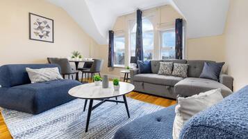 A modern living room with a sofa, a coffee table, and a dining area with chairs and a table.