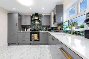 A modern kitchen with grey cabinetry, a black oven, and a marble backsplash. - Huge 9BR London Stay Perfect For Groups, Near Leytonstone Tube & Stratford! (Greater London)