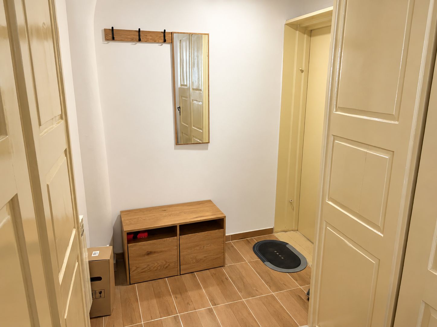 Un couloir avec un banc en bois, un miroir et une porte.