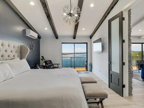 Ein modernes Schlafzimmer mit einem großen Bett, einem Schreibtisch und Blick ins Freie.
