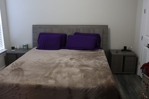 Ein Schlafzimmer mit einem Bett, zwei Nachttischen, einer Kommode und einem Fenster.
