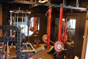 Ein Fitnessstudio mit Gewichte, Spiegeln und einem roten Metallgestell.