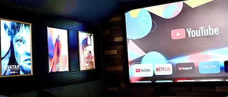 A home theater with a large screen displaying YouTube and other streaming services, surrounded by movie posters.