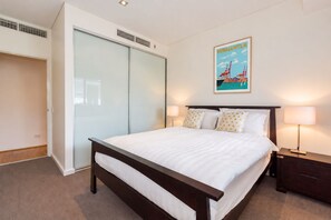 Ein Hotelzimmer mit Bett, Nachttisch, Lampe, Kleiderschrank und einem Bild an der Wand.