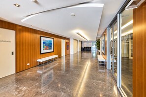 Un pasillo de hotel con suelo de mármol, paneles de madera y bancos.