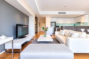 Ein modernes Wohnzimmer mit einem Flachbildfernseher, einem weißen Sofa und einem Couchtisch mit einer Blumenvase.