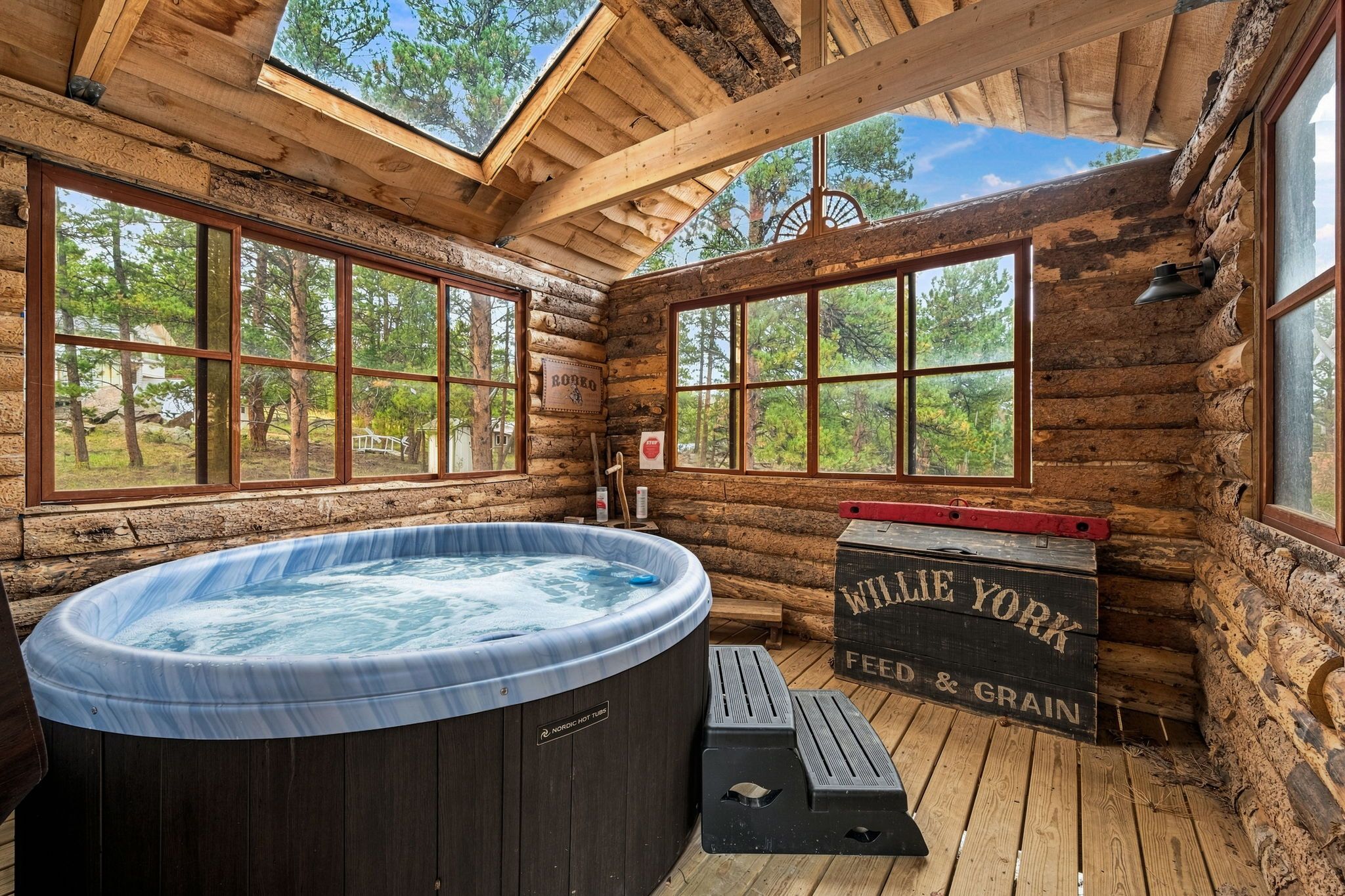 A log cabin with a hot tub, large windows, and a wooden deck.