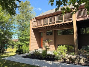 A two-story building with a balcony, a front door, and a landscaped garden. - R10 True Ski-In/Ski-Out w/ ski room, theater room, Morse wood stove - Sleeps 14, Mtn Views (Bretton Woods)