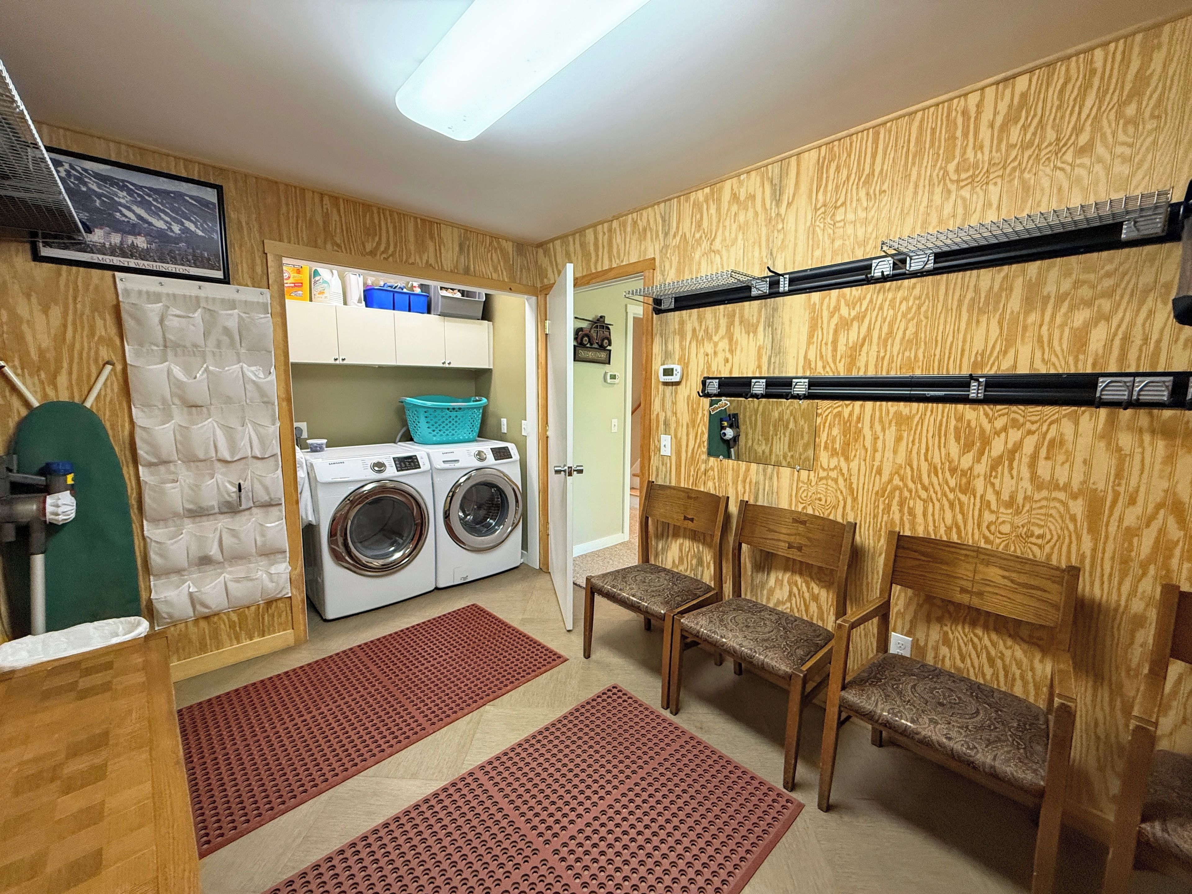 Een wasserette met een wasmachine, droger en planken met schoonmaakmiddelen.