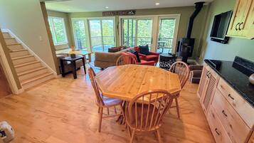 A spacious living area with a wooden dining table, chairs, and a kitchen with wooden cabinets and a black countertop.