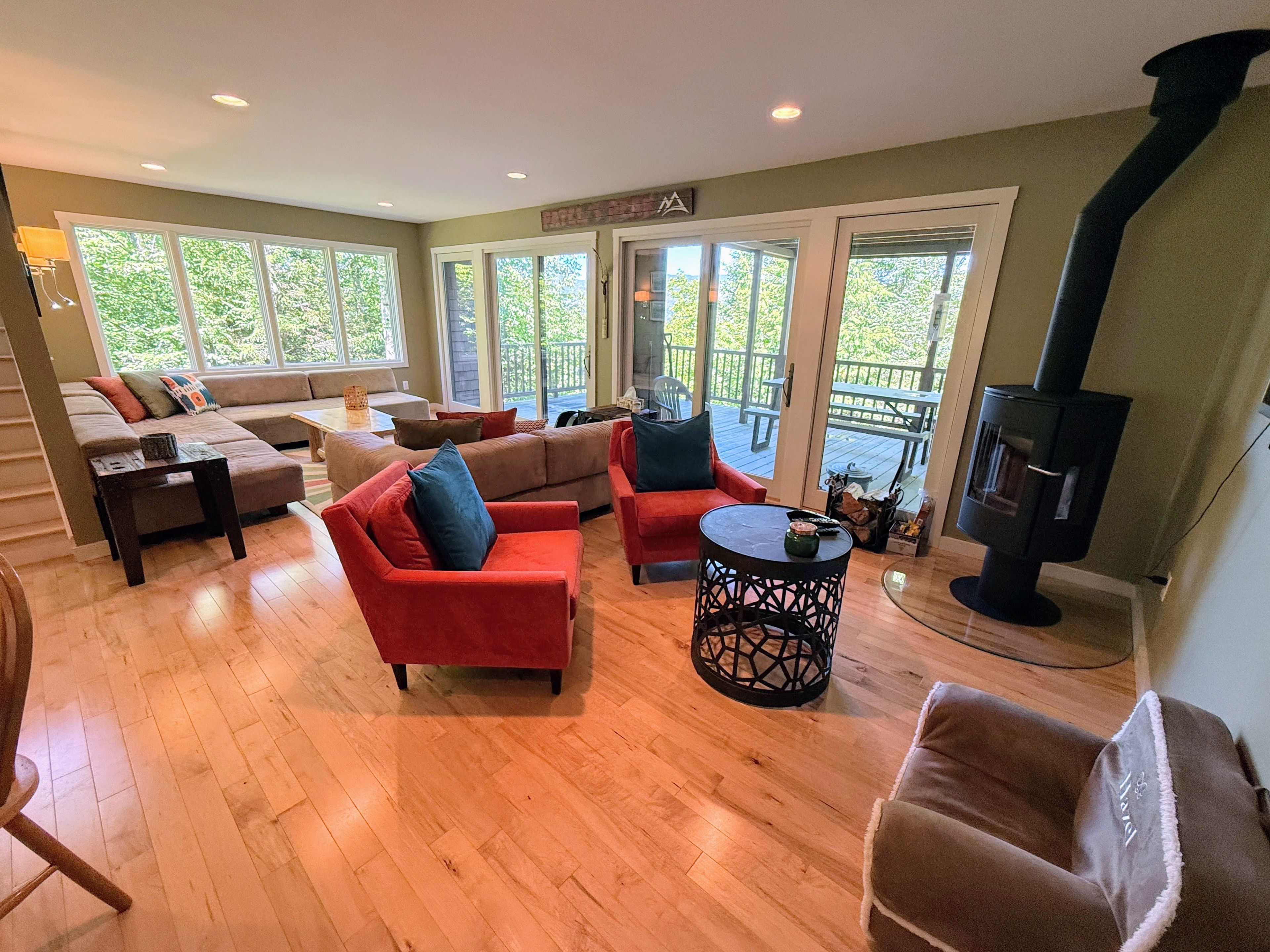 A spacious living room with a fireplace, large windows, and a sliding glass door leading to an outdoor patio.