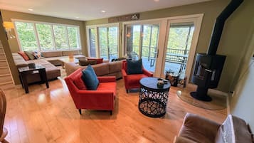 A spacious living room with a fireplace, large windows, and a sliding glass door leading to an outdoor patio.