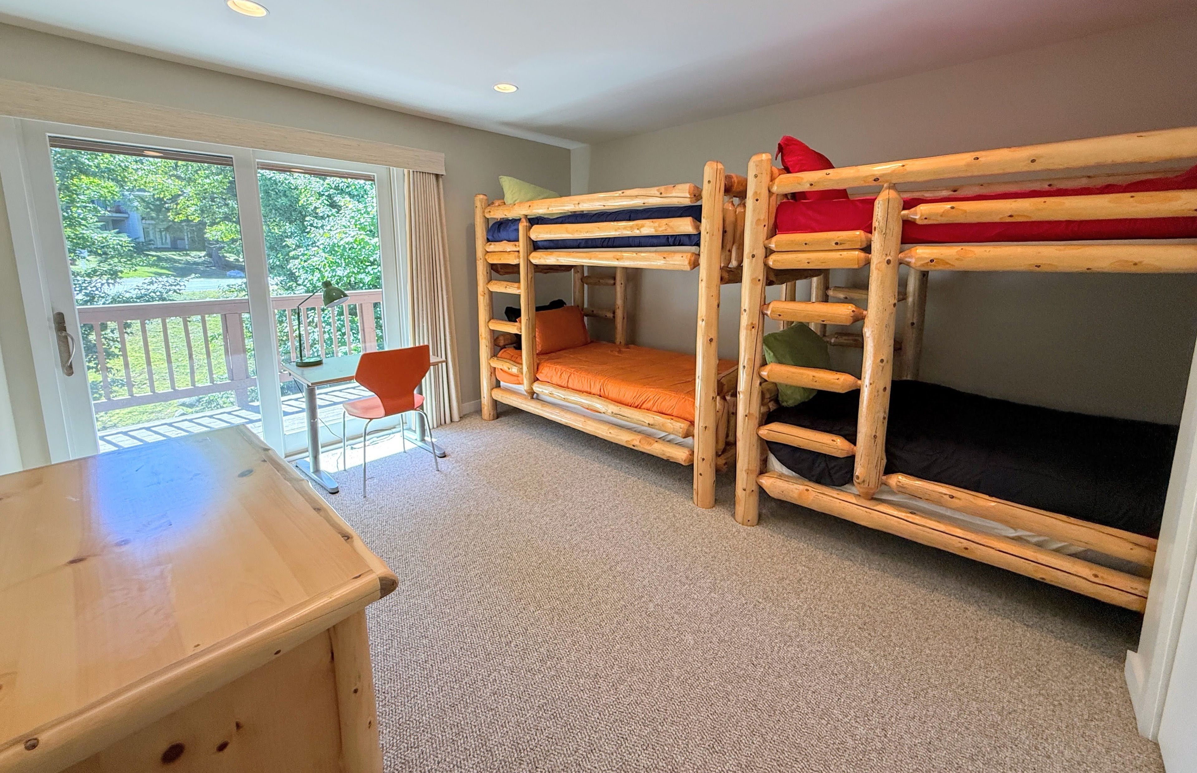 Een kamer met stapelbedden, een bureau en een stoel.