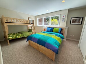 A bedroom with bunk beds, a large bed with a colorful quilt, a window with a view, and a wall with framed pictures. - R10 True Ski-In/Ski-Out w/ ski room, theater room, Morse wood stove - Sleeps 14, Mtn Views (Bretton Woods)