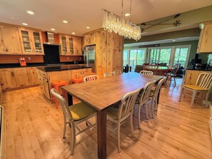 A spacious kitchen with wooden cabinets, a large dining table, and a chandelier. - R10 True Ski-In/Ski-Out w/ ski room, theater room, Morse wood stove - Sleeps 14, Mtn Views (Bretton Woods)