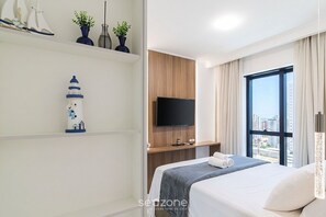 A modern hotel room with a bed, a TV, a city view, and decorative items on the wall. - Apt. w/ Balcony & Sea View 680m Beach Alx1601 (Itapema)