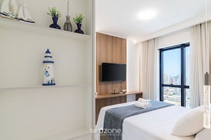 Ein modernes Hotelzimmer mit Bett, Fernseher, Blick auf die Stadt und Dekoration an der Wand.