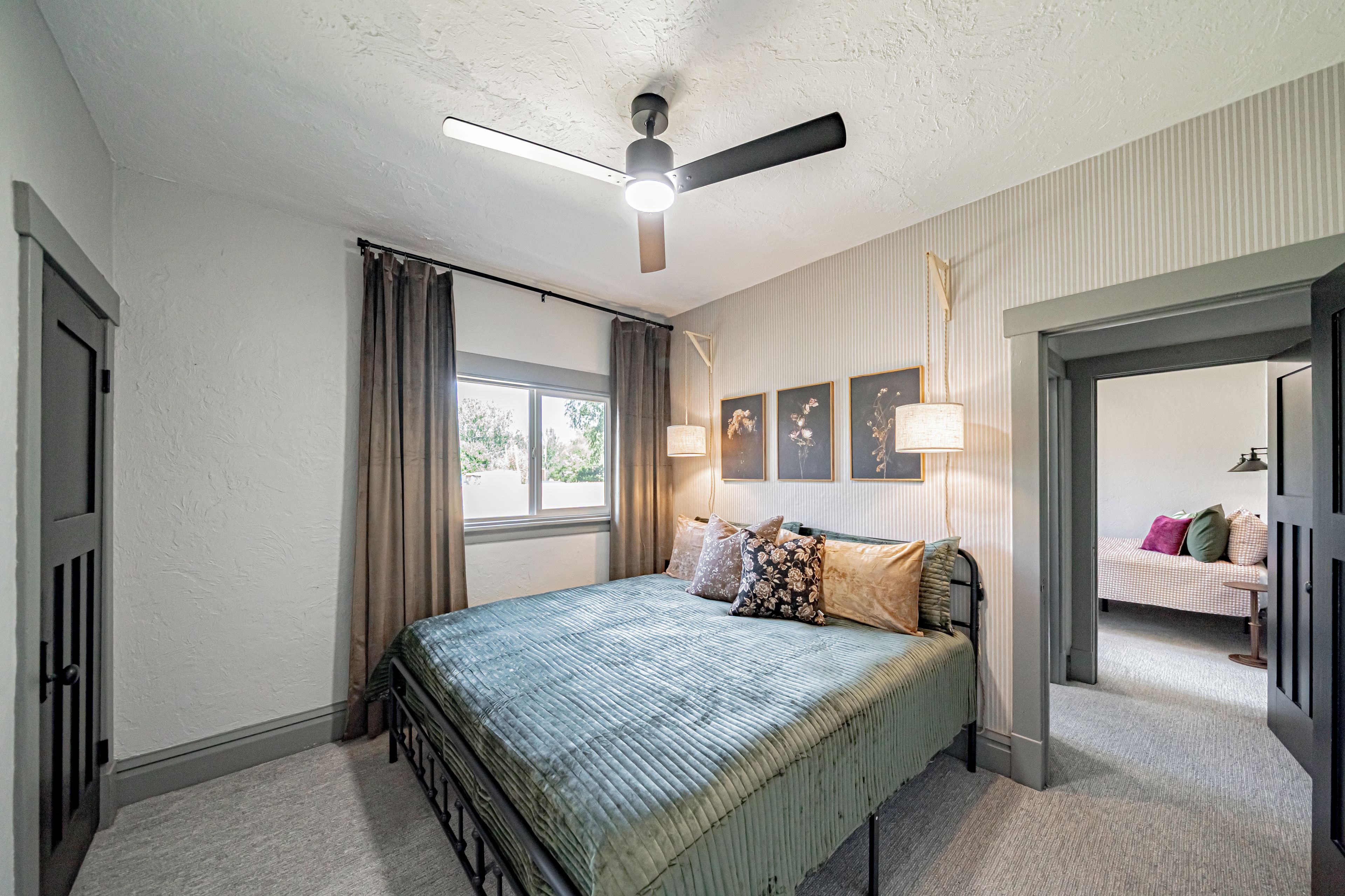 A bedroom with a bed, curtains, a ceiling fan, and a window.