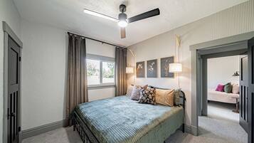 A bedroom with a bed, curtains, a ceiling fan, and a window.