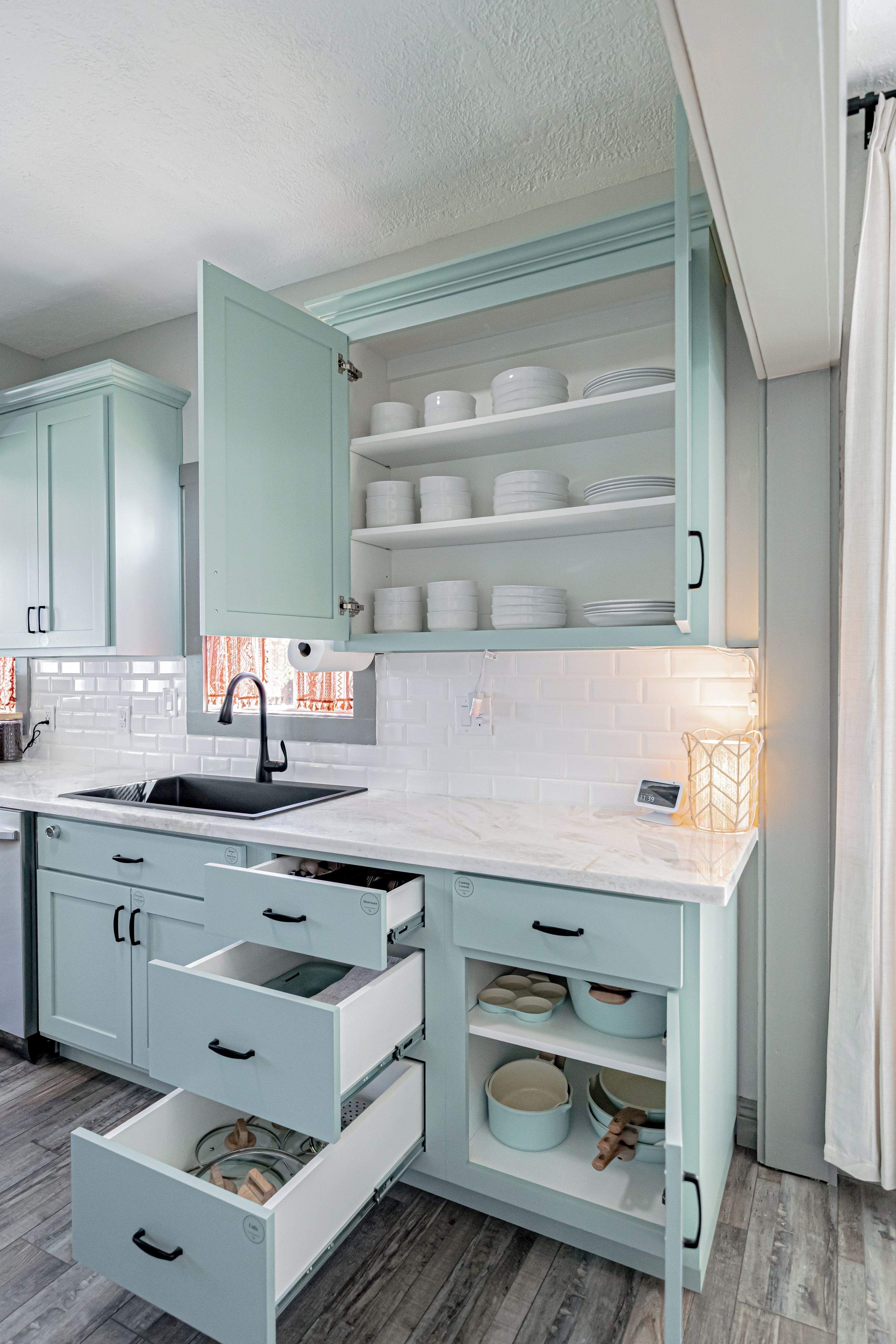 A modern kitchen with light blue cabinets, a white countertop, and a built-in oven.