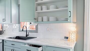 A modern kitchen with light blue cabinets, a white countertop, and a built-in oven.