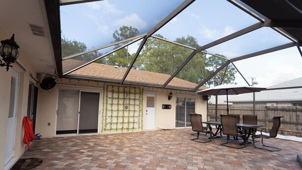 A covered patio with brick flooring, outdoor furniture, and a view of the surrounding area. - Wonderful 3-bedroom townhome with AC in peaceful Wellington (Wellington)