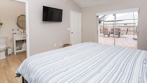 A bedroom with a bed, a TV mounted on the wall, and a sliding glass door leading to an outdoor patio area. - Wonderful 3-bedroom townhome with AC in peaceful Wellington (Wellington)
