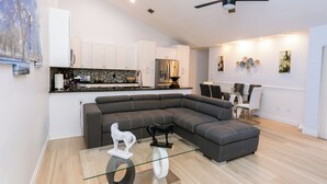 A modern living room with a sectional sofa, a glass coffee table, and a ceiling fan. - Wonderful 3-bedroom townhome with AC in peaceful Wellington (Wellington)
