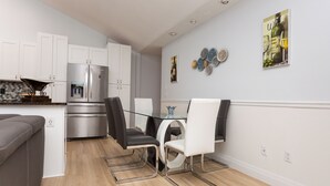 A modern kitchen with white cabinets, a stainless steel refrigerator, and a dining area with a glass table and chairs. - Wonderful 3-bedroom townhome with AC in peaceful Wellington (Wellington)