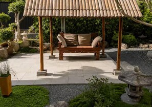 A wooden gazebo with a bench, surrounded by a garden with rocks, plants, and a stone lantern. - Large Stylish Home near CBD - Sleep 10 (Coorparoo)