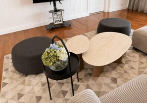 Een woonkamer met een bank, een poef en twee salontafels.